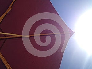 Burgundy beach umbrella against the sky and the scorching sun