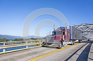 Burgundy big rig classic semi truck with refrigerated shiny semi