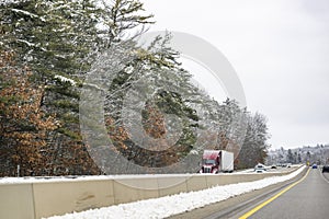 Burgundy big rig long haul semi truck transporting cargo in refrigerator semi trailer driving on the winter highway road with snow