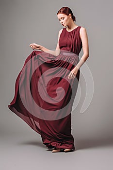 Burgundy chic gown. Red cocktail sleeveless dress with rounded neckline and flying effortless skirt