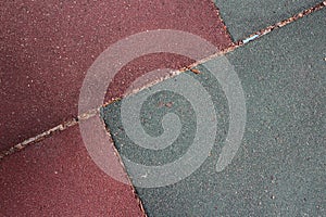 Burgundy and gray artificial turf tiles at a children`s playground placed at an angle