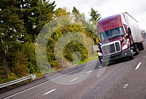 Burgundy modern semi truck and reefer trailer in straight wide h