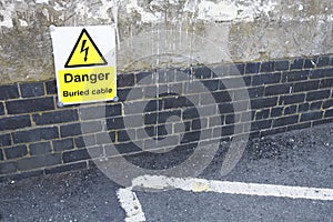 Buried electrical cable danger sign with arrow on road