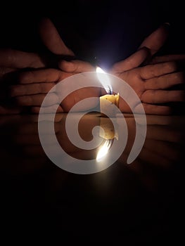 Buring candle, Four hands in background. Dark room