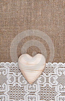 Burlap background with lacy cloth and wooden heart