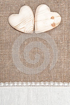 Burlap background with lacy cloth and wooden hearts