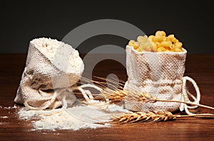 Burlap bags of flour and dry cavatappi pasta, wheat ears