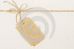 Burlap Cloth Label Tag and Tied Rope Bow over Cardboard Paper