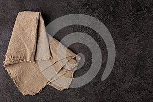 Burlap napkin on a dark structural background, top view