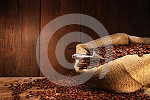 Burlap sack of coffee beans against dark wood