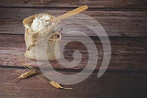 burlap sack with flour in a wooden spoon on a wooden table