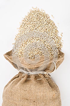 Burlap sack with pearl barley spilling out over a