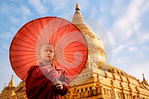 Burmese Buddhist monk walk with umbella in Shwezigon Paya golden pagoda