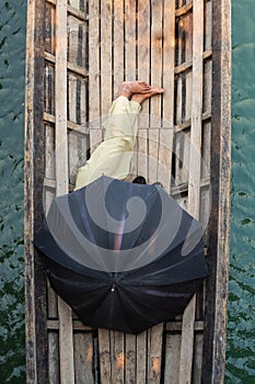 Burmese man sleeping in a boat covered with black umbrella on Inle lake, Myanmar