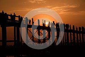 People crossing the longest teak bridge in the world, the iconic wooden U Bein Bridge during sunset, Mandalay, Myanmar