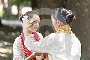 Burmese woman applying Tanakas powder. Southeast Asian young girls with burmese traditional dress visiting a Buddihist temple