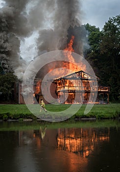 Burn baby burn, a house reflects its flames in the pond.