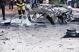 Burned car after an accident on the road. Firefighter standing nearby. Reportage picture of accident