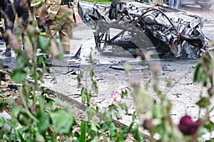Burned car after an accident on the road. Firefighters standing nearby. Reportage picture.