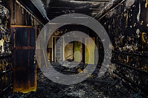 Burned by fire interior of old hospital. Charred walls and doors of corridor
