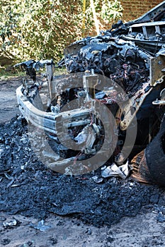 A burned-out car in the courtyard of a residential building. Fire in the car. Danger