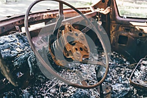 Burned out car, inside view, rusty steering wheel,