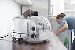 Burned Toasts In Toaster With Woman In Background