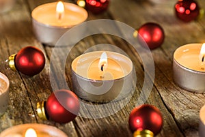 Burning Advent candle flames with red christmas balls ornaments