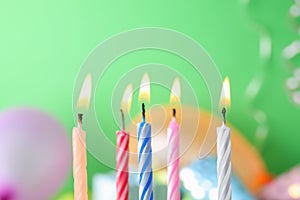 Burning birthday cake candles on color background.