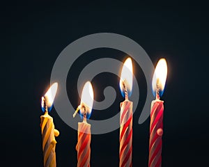 Burning birthday candles on dark background with fire