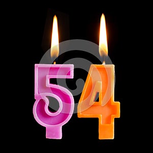 Burning birthday candles in the form of 54 fifty four for cake isolated on black background.