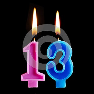 Burning birthday candles in the form of 13 thirteen figures for cake isolated on black background.