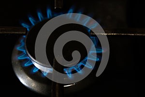 Burning blue gas on the dark stove. Burner gas stove, concept of energy. Closeup, selective focus