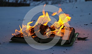 Burning book in snow. pages with the text in open book burn with bright flame