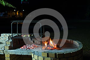 Burning camp fire at dusk in camping site, preparing for barbeque or braai, outdoors activity in South Africa. Selective focus on