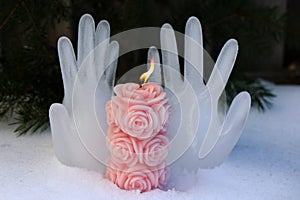 Burning candle on the background of hands made of ice