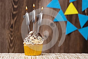 Burning candle - birthday number 111 on wooden background with pennants