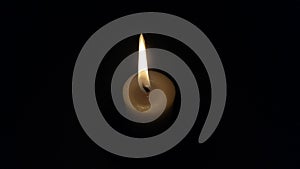 Burning candle on a black background. The candle flame flickers slowly.