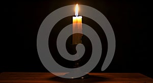 Burning candle in candlestick on black background