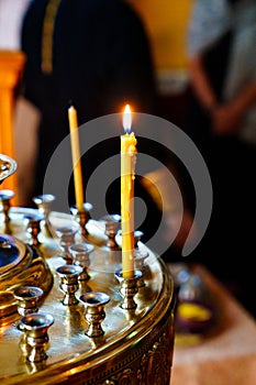 a burning candle in a candlestick in a church.