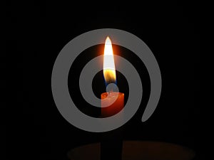 Burning candle in center position and dark background, copyspace.
