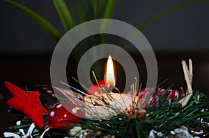 Burning candle and Christmas decoration over snow and wooden background, elegant shot with festive mood