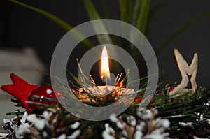 Burning candle and Christmas decoration over snow and wooden background, elegant shot with festive mood