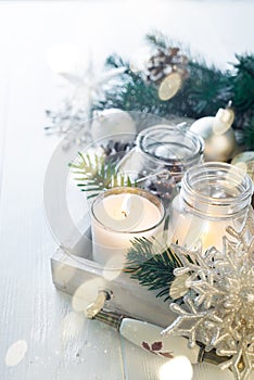 Burning candle and Christmas decoration over snow and wooden background, elegant low-key shot with festive mood