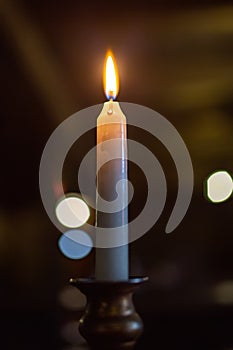 Burning candle on a dark background in an antique candlestick. light
