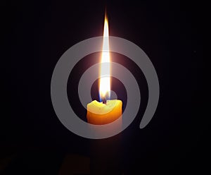 Burning candle on a dark black background