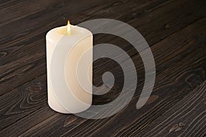 Burning candle on a dark wooden table