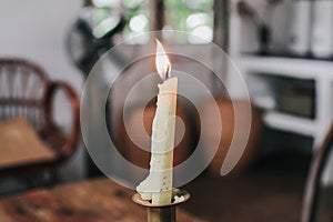 Burning candle on dinner table setup with holiday decorations  in restaurant.