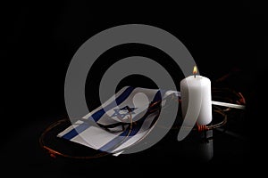 Burning candle and flag of Israel on black background. Holocaust memory day