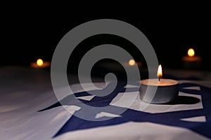 Burning candle on flag of Israel. Holocaust memory day